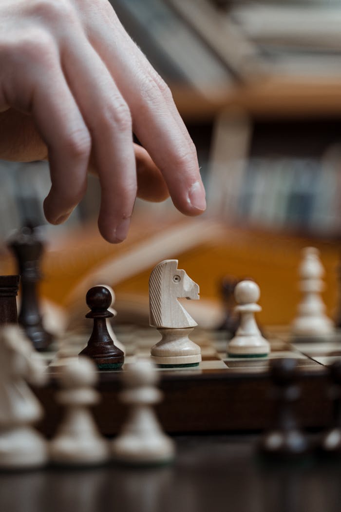Hand poised over a chessboard, selecting a knight for a strategic move in a focused game.